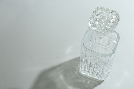 Beautiful crystal bottle casting shadow on light background. Space for textの写真素材