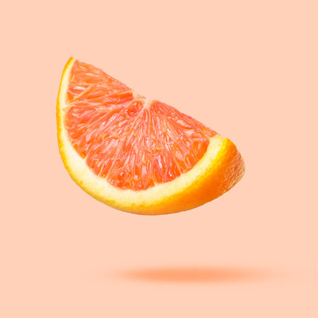 Sliced fresh juicy orange in air on beige pink background. Citrus fruitの写真素材