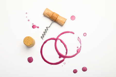 Corkscrew, cork and red wine stains on white background, top viewの写真素材