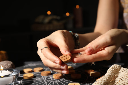 Woman with wooden rune Mannaz at divination mat indoors, closeup