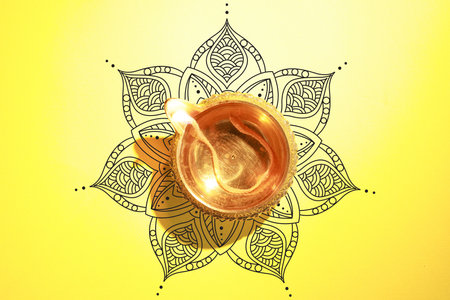 Diwali celebration. Diya lamp on yellow background with pattern, top viewの写真素材