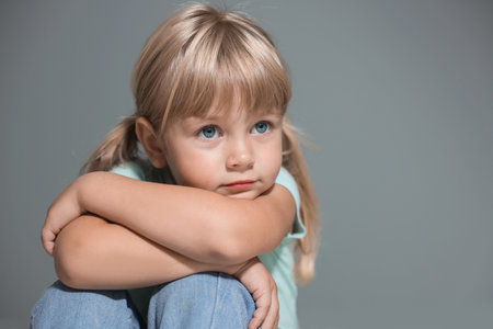 Orphanage concept. Sad little girl on grey background, space for text