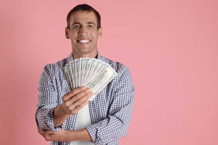 Person holding money on pink background, space for textの写真素材
