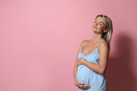 Portrait of beautiful pregnant woman on pink background, space for textの写真素材