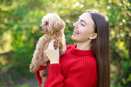 Smiling woman with cute dog in autumn parkの写真素材