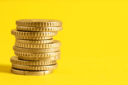 Salary concept. Stacked coins on yellow background, closeup. Space for textの写真素材