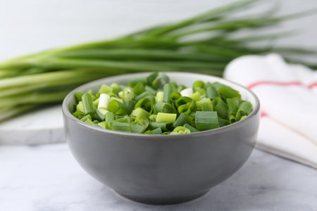 Chopped green onion in bowl on white table, closeupの写真素材
