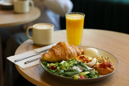 Tasty breakfast. Freshly baked croissant and salad served on wooden table in cafe, closeupの写真素材