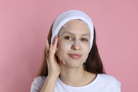 Teenage girl with sheet facial mask on pink background. Acne treatmentの写真素材