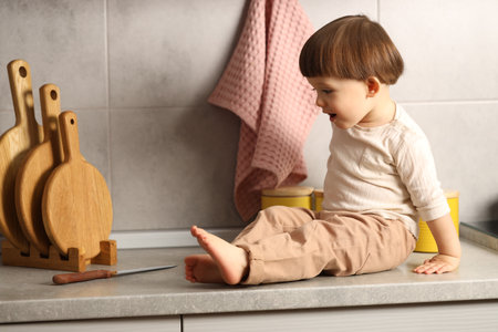 Little boy near knife on kitchen counter. Dangerous situationの写真素材