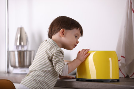 Little boy playing with toaster in kitchen. Dangerous situationの写真素材