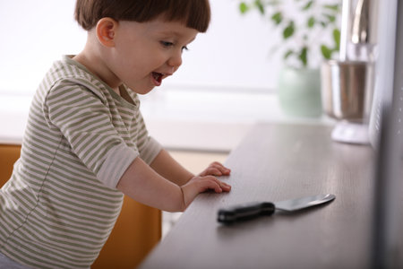 Little boy reaching towards knife on kitchen counter. Dangerous situationの写真素材