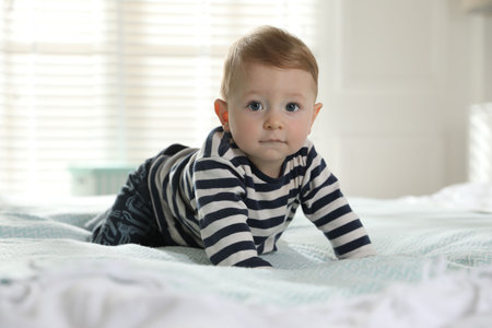 Cute little baby on bed at homeの写真素材