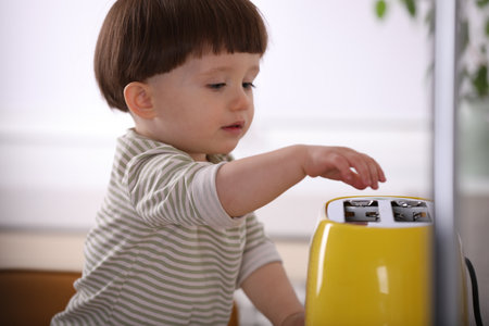 Little boy playing with toaster in kitchen. Dangerous situationの写真素材