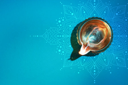 Diwali celebration. Diya lamp on light blue background with pattern, top view. Space for textの写真素材
