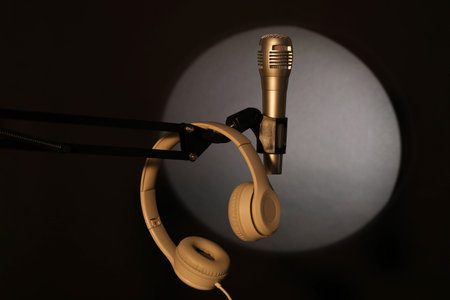 Stand with microphone and headphones in spotlight on black background. Sound recording and reinforcementの写真素材