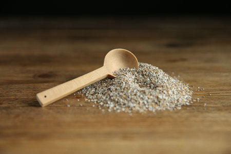 Pile of fresh rye bran and spoon on wooden table, closeupの写真素材