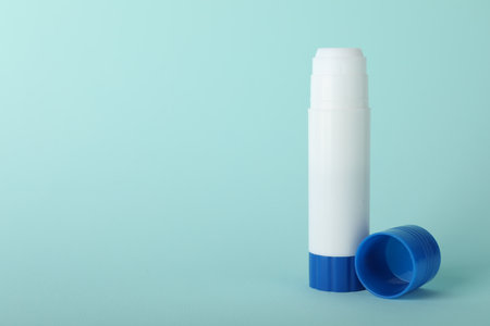 Glue stick and cap on light blue background, space for textの写真素材