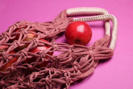 Handmade macrame shopping bag with apples on crimson background, closeupの写真素材