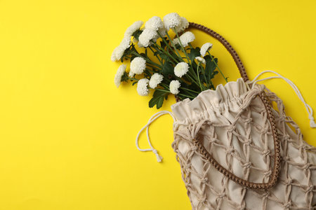 Macrame shopping bag with flowers on yellow background, top view. Space for textの写真素材