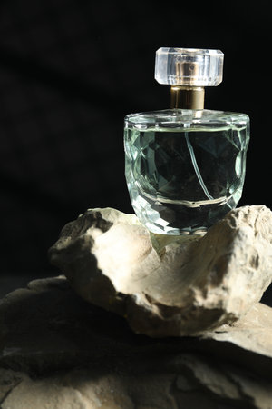 Bottle of fragrant perfume on rock against dark backgroundの写真素材
