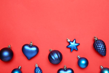 Blue Christmas baubles on red background, flat lay. Space for textの写真素材