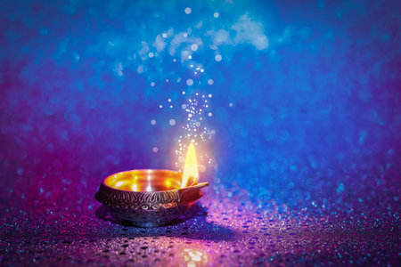 Happy Diwali celebration. Diya lamp burning on color background. Space for text. Bokeh effect