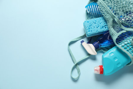 Cleaning products and tools in bag on light blue background, top view. Space for textの写真素材