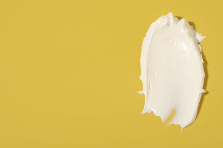 Cream on yellow background, top view and space for text. Sample of cosmetic productの写真素材