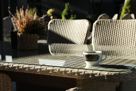 Table with cup of coffee, flowers and chairs in outdoor cafe, closeupの写真素材