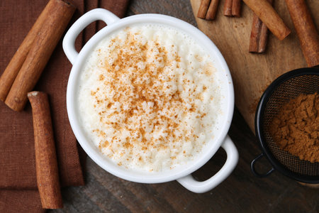 Delicious rice pudding with cinnamon on wooden table, flat layの写真素材