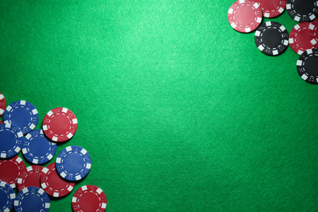 Poker chips on green table, flat lay. Space for text