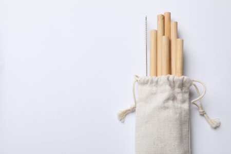Bamboo drinking straws and cleaning brush in bag on white background, top view. Space for textの写真素材