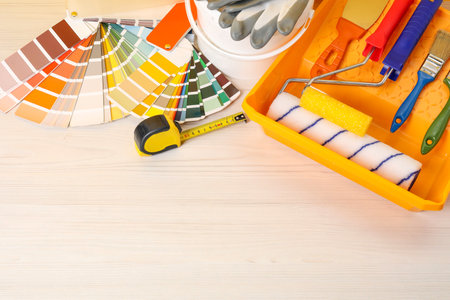 Decorating and design. Different painter's tools on white wooden table, flat lay. Space for text