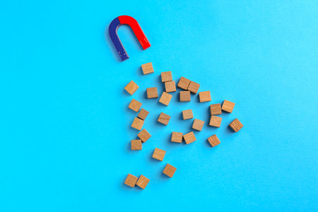 Magnet attracting wooden cubes on light blue background, flat layの写真素材