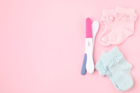 Pregnancy tests and socks on pink background, top view. Space for textの写真素材