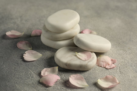 Spa stones and petals on gray table, closeup
