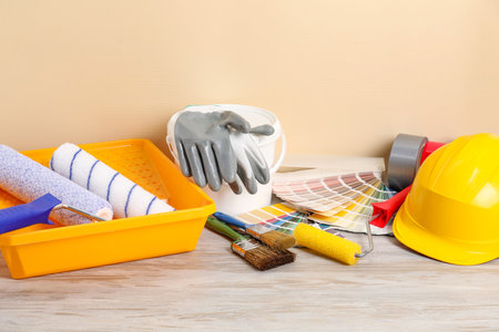 Different painter's tools on light wooden table. Decorating and design