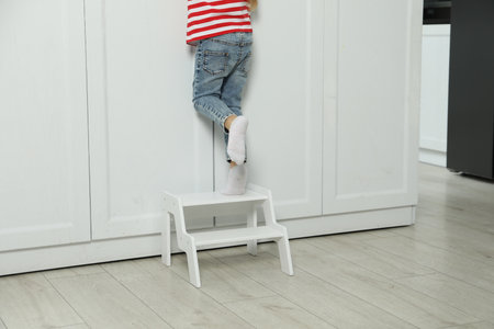 Little girl standing on step stool indoors, closeup