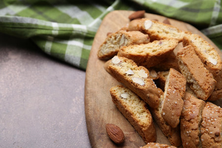 Tasty almond biscuits (Cantuccini) and nuts on brown textured table, closeup. Space for textの写真素材