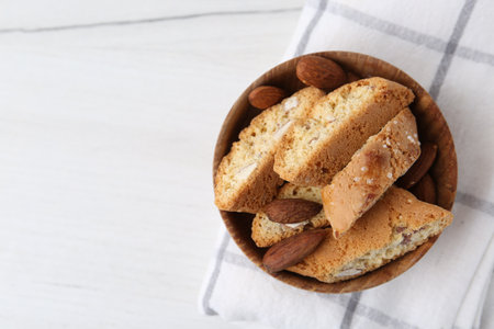 Tasty almond biscuits (Cantuccini) and nuts in bowl on white table, top view. Space for textの写真素材