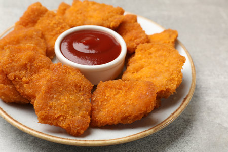 Delicious chicken nuggets with ketchup on gray textured table, closeupの写真素材