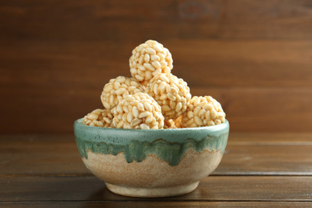 Delicious puffed rice balls in bowl on wooden table, closeupの写真素材
