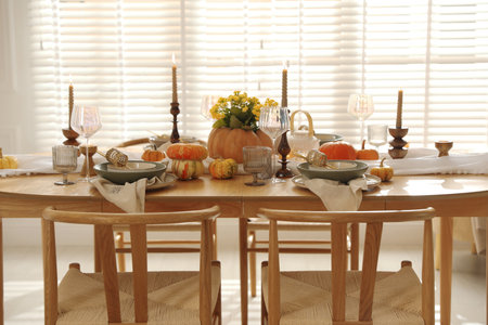 Stylish table setting with beautiful dishware, glasses and autumn decor in dining roomの写真素材