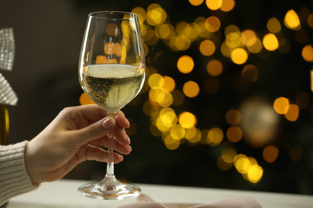 Woman with glass of white wine at table against blurred Christmas lights, closeup and space for text. Bokeh effectの写真素材