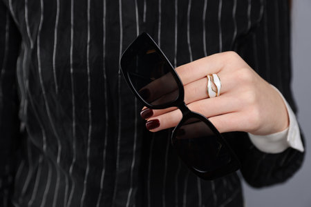 Teenage girl with sunglasses and stylish ring on gray background, closeupの写真素材