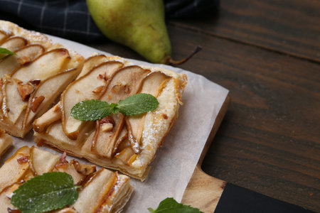 Tasty puff pastry pie with pears and mint on wooden table, closeupの写真素材