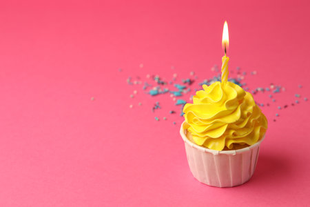 Tasty cupcake with burning candle on pink background, space for textの写真素材