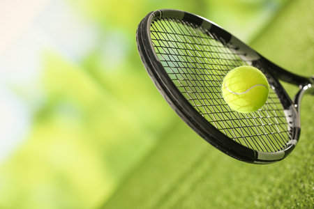 Tennis racket with ball on green artificial grass, closeup. Space for textの写真素材