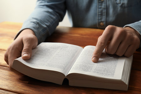 Man reading Holy Bible in English language at wooden table, closeupの写真素材